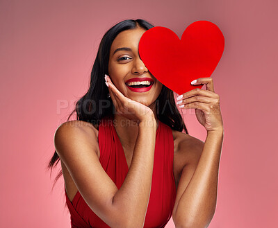 Buy stock photo Woman, paper heart and smile in studio portrait for makeup, beauty or romantic sign by red background. Happy girl, fashion model or cardboard emoji for love, cosmetic or happy for valentines day date