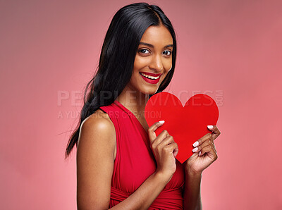 Buy stock photo Portrait, heart and valentines day with a woman on a pink background in studio for love or romance. Smile, emoji and social media with a happy young female holding a shape or symbol of affection