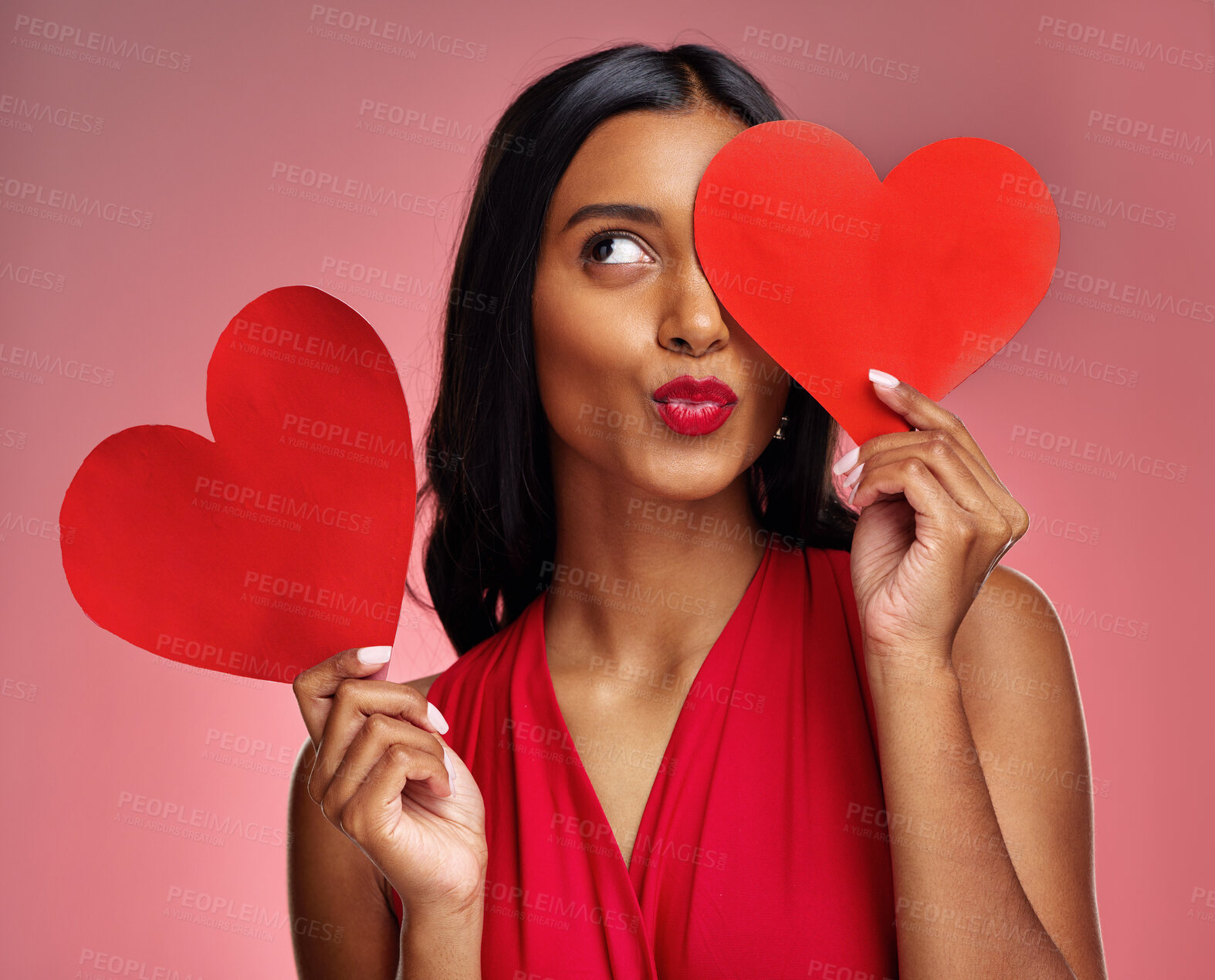 Buy stock photo Red heart, woman in studio and kiss emoji on background for romance, emotion and fun symbol. Happy indian female model, thinking and pout with paper shape for love, icon or flirting on valentines day