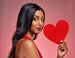 Portrait, heart and love with a woman on a pink background in studio for romance on valentines day. Face, emoji and social media with a confident young female holding a shape or symbol of affection