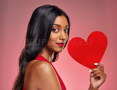 Buy stock photo Portrait, heart and love with a woman on a pink background in studio for romance on valentines day. Face, emoji and social media with a confident young female holding a shape or symbol of affection