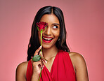 Excited, beauty and face of a woman with a rose on a studio background for valentines day. Makeup, model and happy young Indian girl with a flower in hand for romance or love on pink backdrop