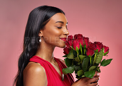 Face, beauty and a woman smelling a roses on a studio background for valentines day. Makeup, model and happy young Indian girl profile with a flower bouquet for romance or love on pink backdrop