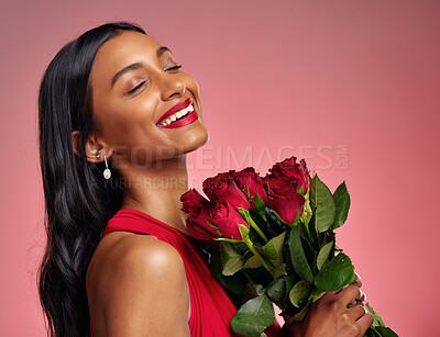 Face, beauty and smile of a woman with a roses on a studio background for valentines day. Makeup, model and happy young Indian girl with a flower bouquet for romance or love on a pink backdrop