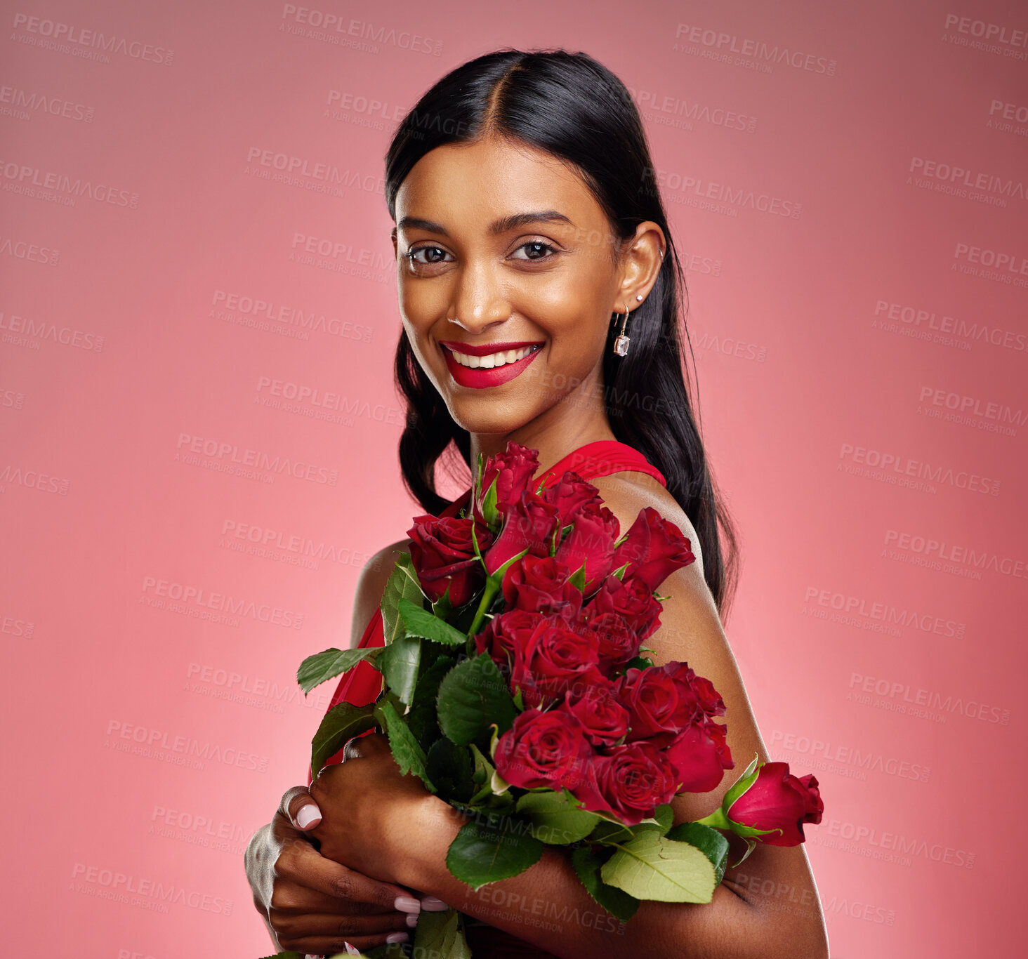 Buy stock photo Pageant, flowers and portrait of an Indian woman on a studio background for valentines day. Smile, happy and a young model or girl with a floral bouquet on a red backdrop for luxury present of roses