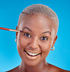 Portrait, makeup and eyeshadow with a black woman on a blue background in studio to apply a beauty product. Face, gold color on a brush and a happy young female model posing for style or glamour