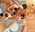 Breakfast, food and hungry people in dining room, eating healthy and above table setting or home in the morning. Fruit, pancakes and hands on strawberry or muffin plate for nutrition or diet