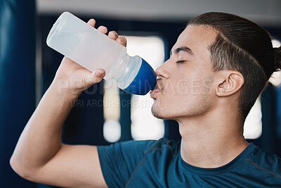 Buy stock photo Thirsty, fitness and a man drinking water after exercise at the gym for wellness and health. Hydration, young and a male athlete with a bottle for liquid after cardio, workout or training on a break