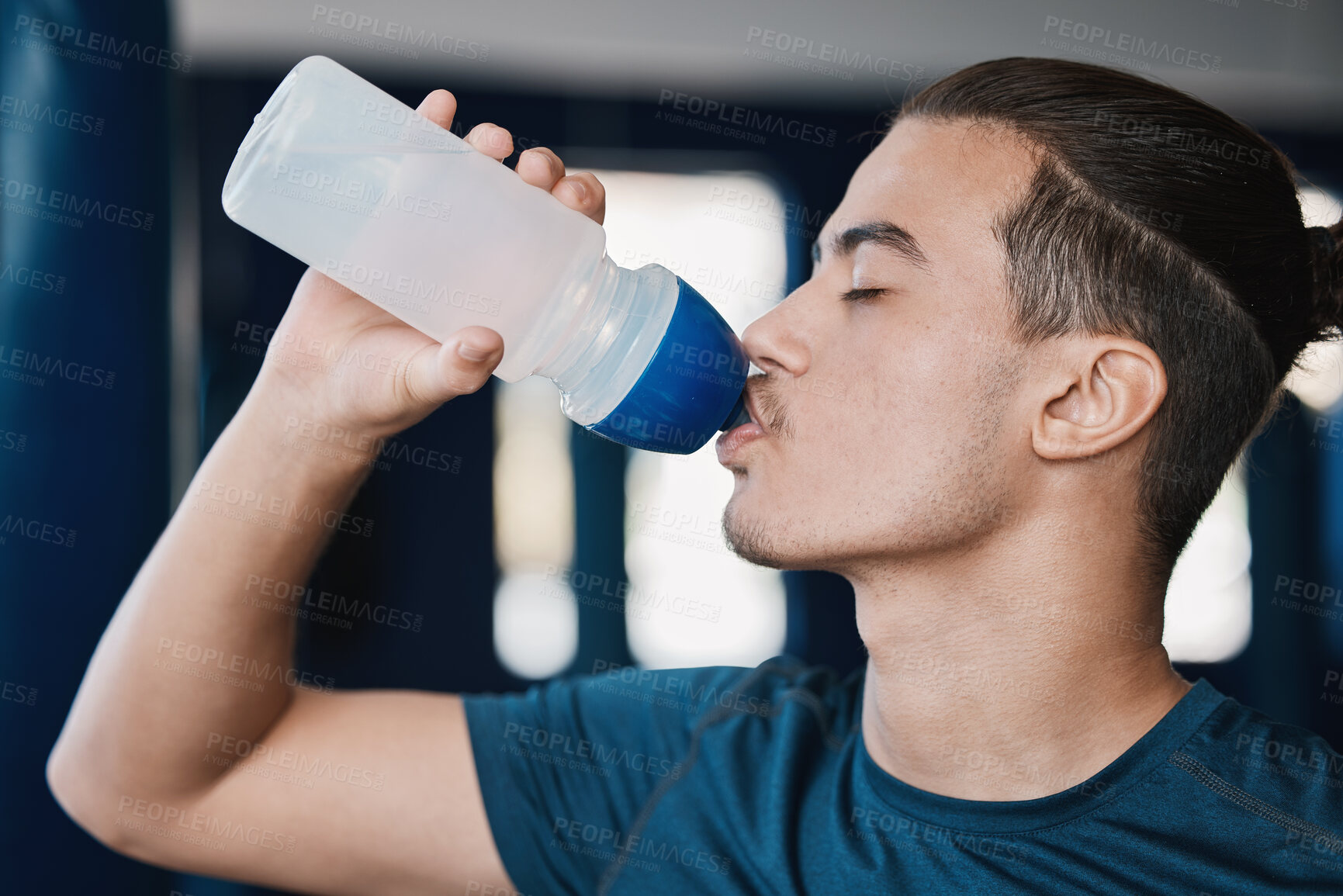 Buy stock photo Thirsty, fitness and a man drinking water after exercise at the gym for wellness and health. Hydration, young and a male athlete with a bottle for liquid after cardio, workout or training on a break