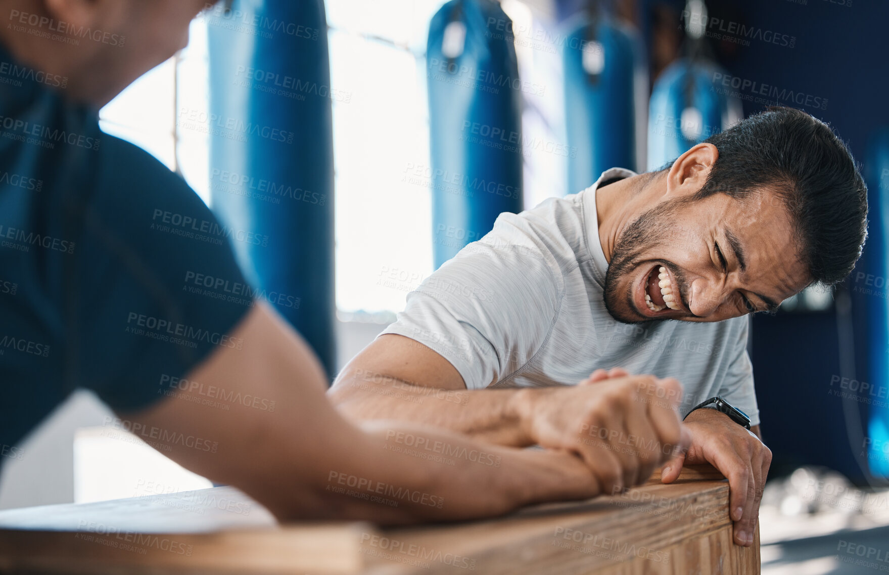 Buy stock photo Strength, motivation and men arm wrestling in a gym on a table while being playful for challenge. Rivalry, game and male people or athletes doing strong muscle battle for fun, bonding and friendship.