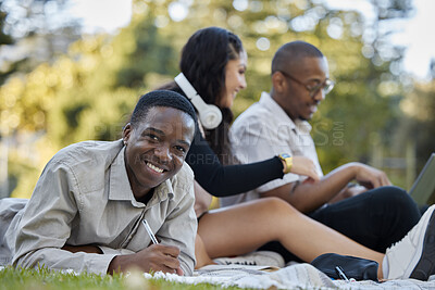Buy stock photo Nature, university and portrait of a man studying on the grass with his friends for a test or exam. Happy, smile and African male student writing assignment in his notebook in park at college campus.