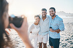 Happy, photo and friends at the beach with a photographer for summer memory, holiday or bonding. Smile, camera and a woman taking a picture of a group of people at the ocean during a vacation