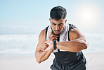 Man, fitness and checking watch for pulse, heart rate or performance on break after workout on the beach. Fit, active and sporty male person with wristwatch for monitoring body exercise by the ocean