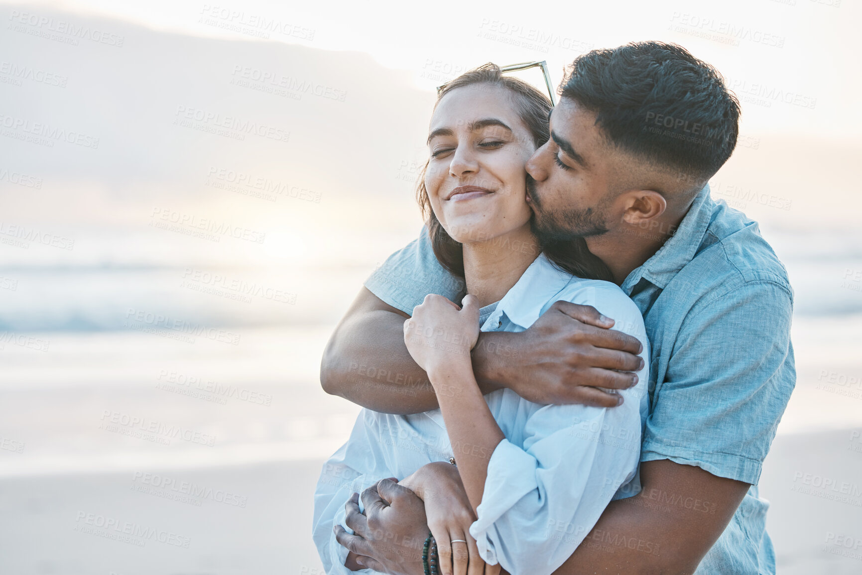 Buy stock photo Couple, hug and kiss on beach with love, travel and holiday with mockup space and happy together outdoor. Summer, support and care with affection, man and woman in nature with adventure by the ocean