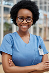 Portrait, nurse and black woman with arms crossed, smile or happy in hospital. African medical professional, confidence and face of surgeon from Nigeria with glasses for healthcare service in clinic.