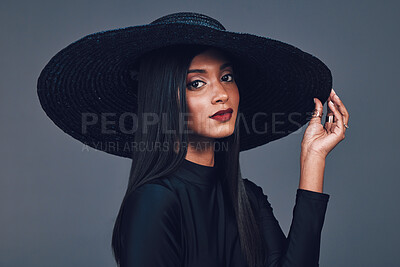 Buy stock photo Face, fashion and serious woman with hat in studio isolated on a gray background. Portrait, style and confident female model from India with makeup cosmetics, classy clothes and elegant aesthetic.