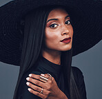 Fashion, face and confident woman with hat in studio isolated on a gray background. Portrait, style and serious female model from India with makeup cosmetics, classy clothes and elegant aesthetic.