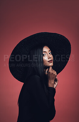 Buy stock photo Portrait, fashion and confident woman with hat in studio isolated on red background mockup space. Face, style and serious model from India with makeup cosmetics, classy clothes and elegant aesthetic.
