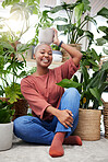Portrait of a black woman, garden and happy with plant on head and care for plants, leaves and sunshine in greenhouse. Gardening, growth and person with pride for houseplant, cactus or aloe vera