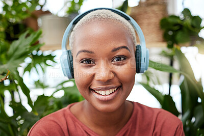 Buy stock photo Portrait, music and headphones with a black woman in her home by plants while streaming an audio playlist. Face, radio and subscription service with a carefree young female person in her house