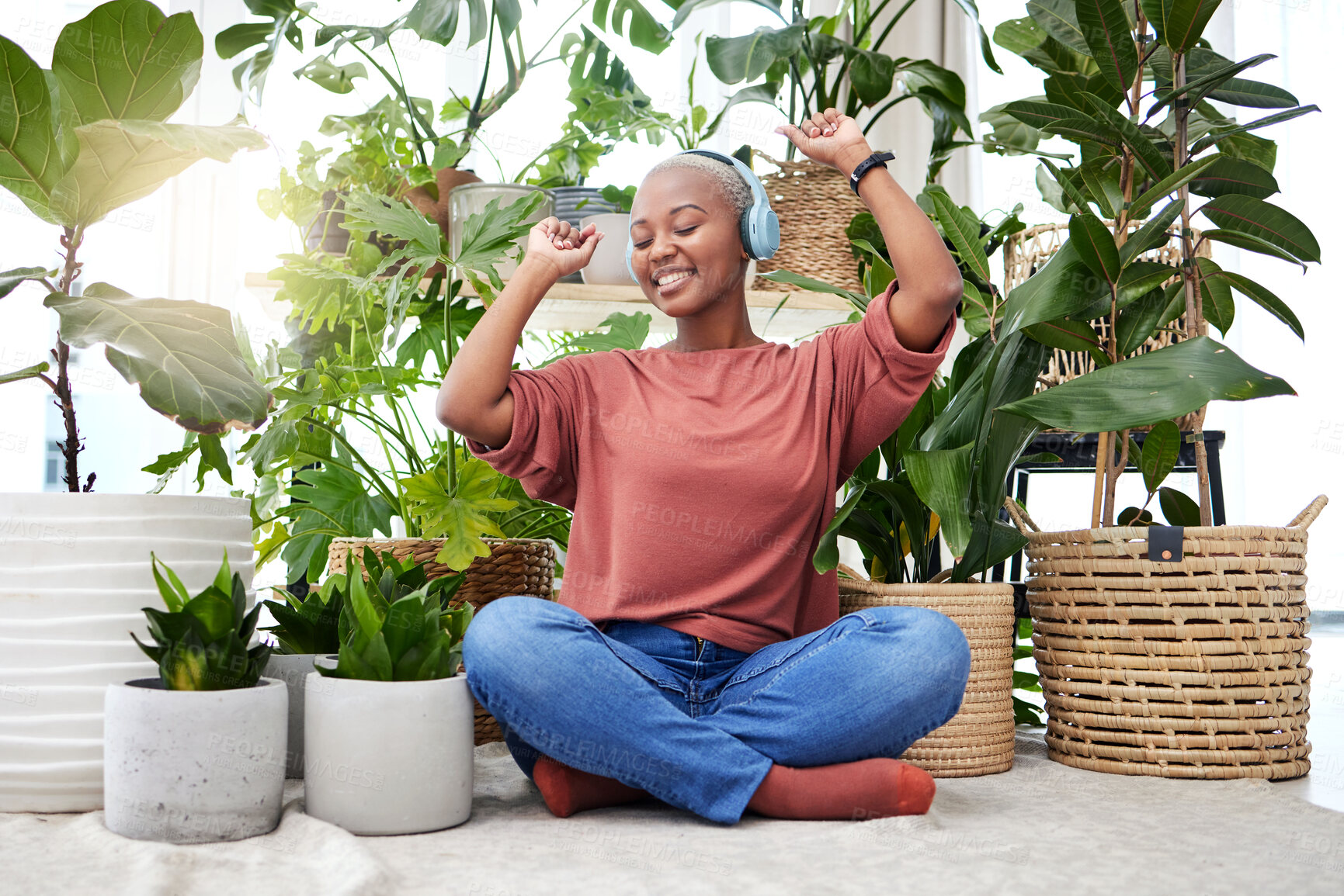 Buy stock photo Music, dance and radio with a black woman in her home by plants while streaming an audio playlist. Freedom, headphones and subscription service with a carefree young female person in her house