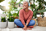 Music, dance and thinking with a black woman in her home by plants while streaming an audio playlist. Headphones, radio and subscription service with a carefree young female person in her house