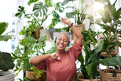 Buy stock photo Music, dance and headphones with a black woman in her home by plants while streaming an audio playlist. Freedom, radio and subscription service with a happy young female person eyes closed in a house