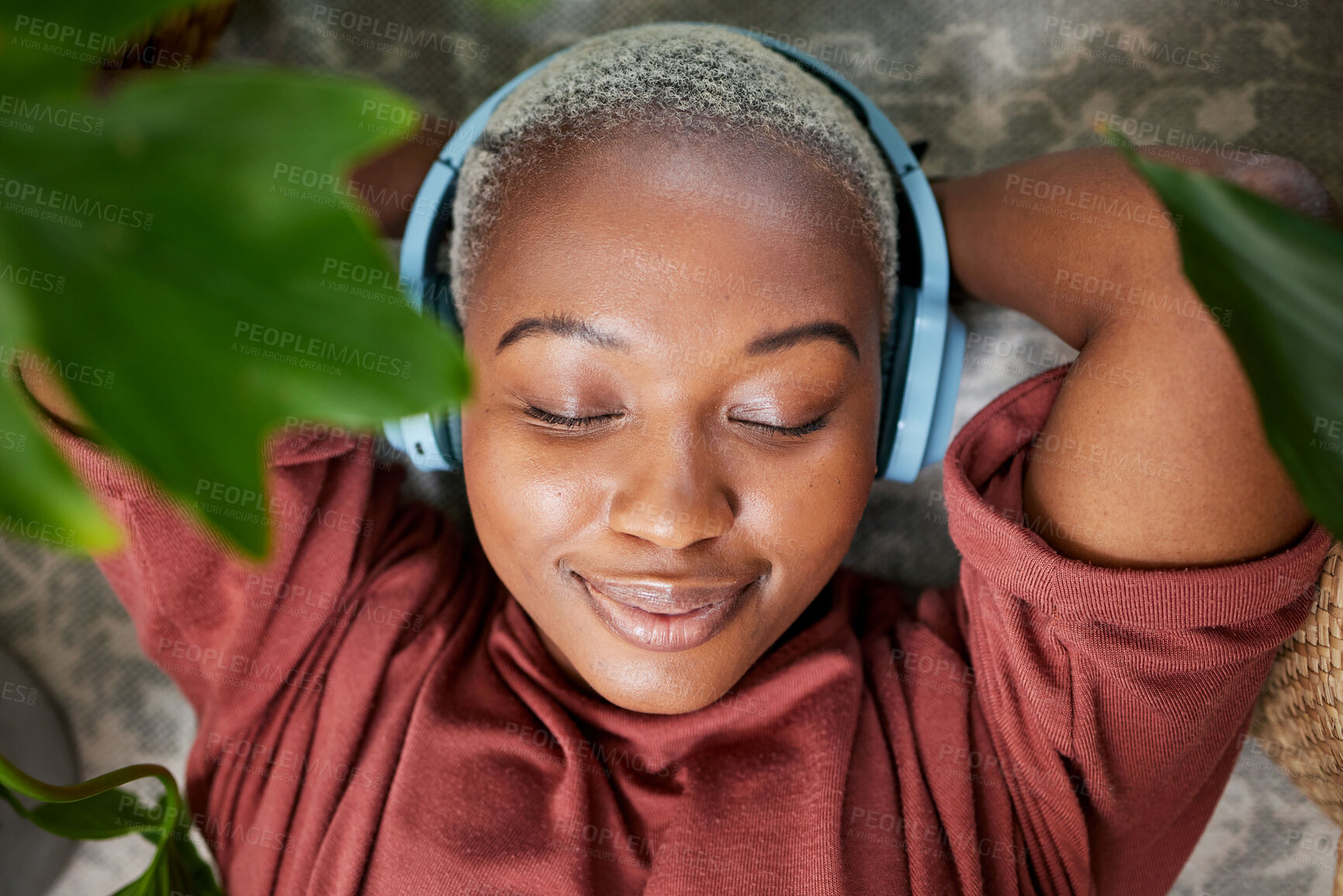 Buy stock photo Woman, face and headphones for listening to music to relax on a floor with plants for peace and calm. Headshot of a black female person meditate with sound, audio and podcast or radio at home