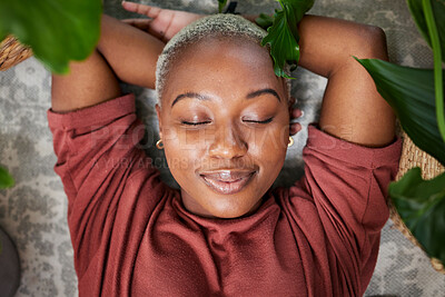 Buy stock photo Relax, plants and above of black woman in home for wellness, zen mindset and calm energy. Nature, happy and face of female person laying on floor with eco friendly ferns, leaves and house plant