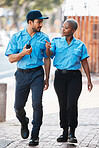 Security guard, safety officer and team walking on street for protection, patrol or watch. Law enforcement, talking and duty with a crime prevention man and black woman in uniform outdoor in the city