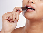 Chocolate, bite and mouth of woman with sweets in studio eating luxury food, treats and candy. Sugar, calories and face closeup of female person with cocoa bar, dessert and snack on white background