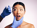Woman, needle and fear on face in studio for surgery, cosmetics and shock with collagen by white background. Japanese patient, doctor and syringe for dermatology, change and pain for skin aesthetic