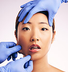 Asian woman, surgery and pinch facial skin in studio for cosmetic, inspection and hands in gloves by white background. Beauty, doctors and check for patient, transformation or shock for pain on face