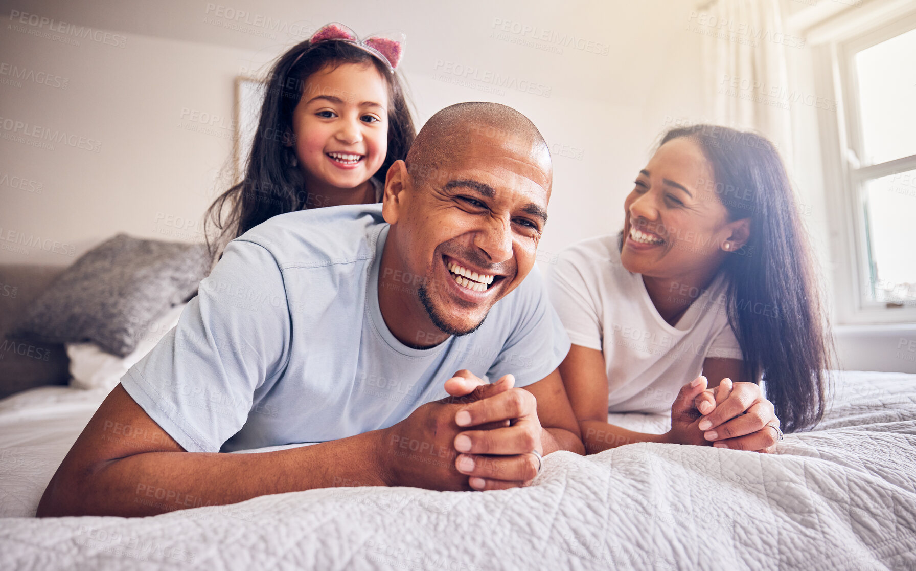 Buy stock photo Mother, father and child laughing on a bed in a family home while happy and playing for quality time. Man, woman or parents and girl kid together in the bedroom for morning bonding with love and care