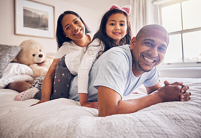 Buy stock photo Family portrait, morning and relax on a bed at home while happy and playing for quality time. Man, woman or hispanic parents and a girl kid together in the bedroom for bonding with love and care