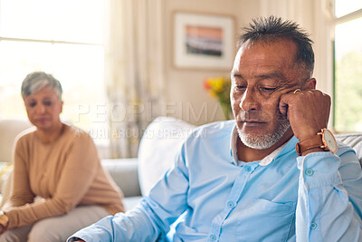 Buy stock photo Couple arguing, stress and divorce with a senior man on a sofa in the living room of his home after a fight. Sad, anxiety or depression with an elderly male pensioner looking down after an problem