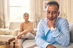 Couple fighting, stress and divorce with a senior man on a sofa in the living room of his home after an argument. Sad, anxiety or depression with an elderly male pensioner looking down after conflict