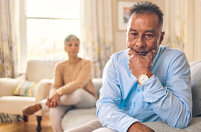 Buy stock photo Couple fighting, stress and divorce with a senior man on a sofa in the living room of his home after an argument. Sad, anxiety or depression with an elderly male pensioner looking down after conflict