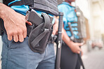 Man, hands and police with gun in holster to protect and serve in city for health or safety in street. Closeup of male person, cop or security guard and firearm for law enforcement protection in town