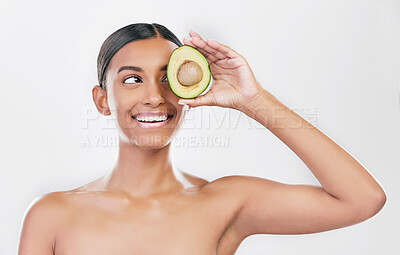 Buy stock photo Avocado, eye skincare and happy woman isolated on a white background for healthy facial and cosmetics ideas. Indian person or beauty model thinking of green, vegan or dermatology product in studio