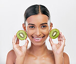 Skincare, health and portrait of a woman with kiwi for nutrition, diet and wellness. Happy, spa treatment and an Indian girl or model with fruit or food for facial isolated on a white background