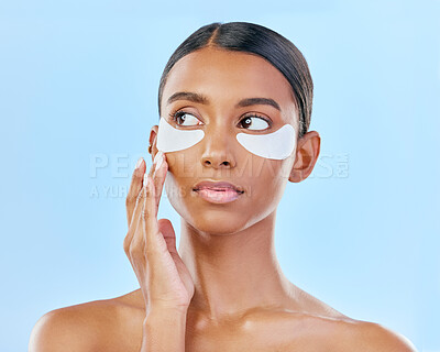 Buy stock photo Face, eye patch and beauty of a woman with natural skin glow on a blue background. Dermatology, collagen mask and cosmetics of Indian female model for facial shine, wellness or self care in studio