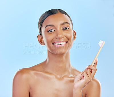 Toothbrush, portrait and a woman brushing teeth for dental health on a blue background for wellness. Happy indian female model with toothpaste and brush for a clean, fresh and healthy mouth in studio