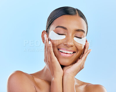 Buy stock photo Beauty, eye patch and face of a woman with natural skin glow on a blue background. Dermatology, collagen mask and cosmetics of Indian female model for facial shine and touch for self care in studio
