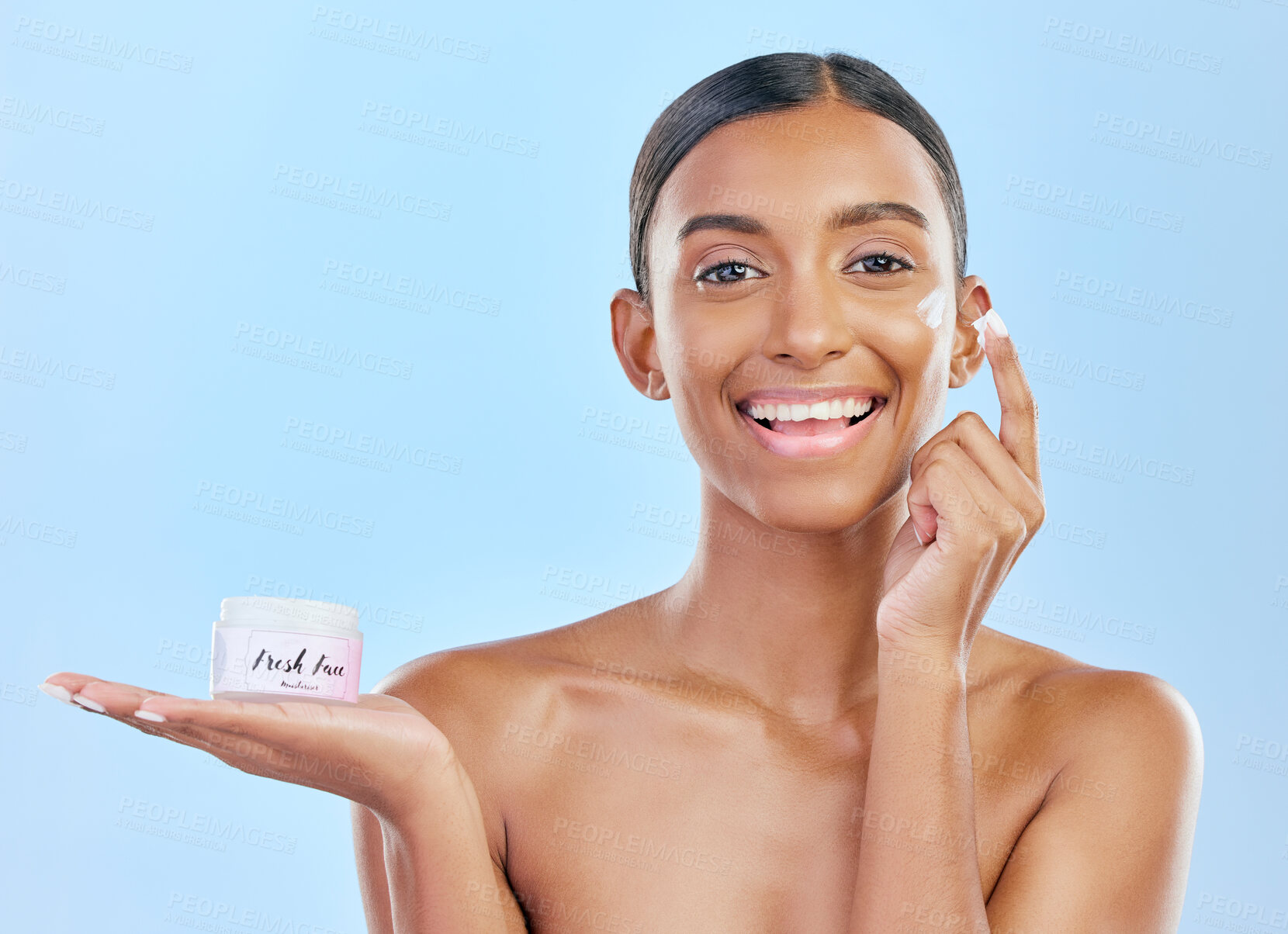Buy stock photo Face cream, skin and beauty portrait of a happy woman with natural glow on a blue background. Dermatology, moisturizer and cosmetics of Indian female model with a product container on hand in studio