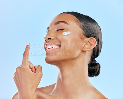Buy stock photo Face cream, skin and beauty of a happy woman with natural glow on a blue background. Dermatology, moisturizer and cosmetics of an Indian female model for facial shine, wellness or self care in studio