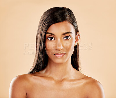 Buy stock photo Face, skin and beauty portrait of a woman with natural glow on a beige background. Dermatology, makeup and cosmetics of serious Indian female model for facial shine, hair care or self love in studio