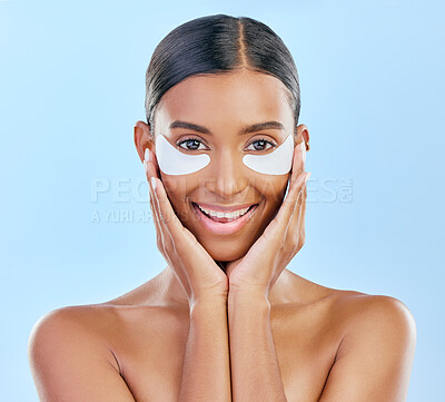 Buy stock photo Beauty, skincare and portrait of woman with patches for eyes, dark circles and treatment. Smile, spa and Indian girl or model with a facial product for a glow isolated on a blue background in studio