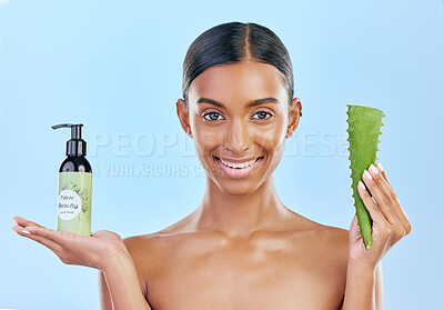 Buy stock photo Woman, aloe vera and skincare in studio portrait with smile, natural choice and happy by blue background. Girl, model and cactus plant for health, wellness and bottle with serum, care and facial glow