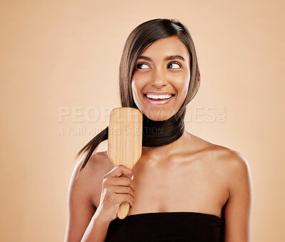 Buy stock photo Face, smile and a woman brushing her hair in studio on a cream background for natural or luxury style. Haircare, thinking and shampoo with a young indian female model at the salon or hairdresser